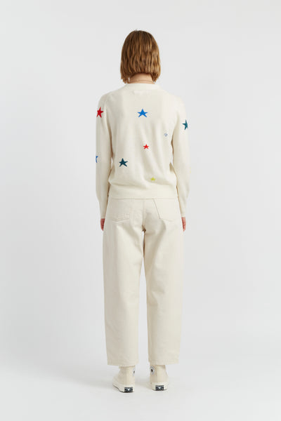 Person wearing a cream-colored outfit with colorful star patterns on a white background