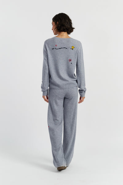 Person wearing a gray sweatshirt with colorful patches on the back, standing against a white background
