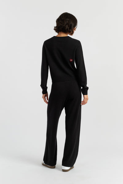 Person wearing a black outfit with a small red detail on a white background