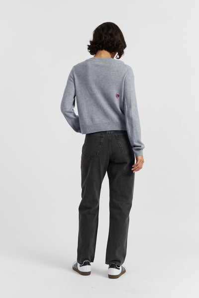 Person wearing a gray sweater and dark pants on a white background