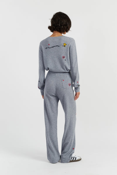 Person wearing a gray tracksuit with embroidered designs on a white background