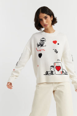Woman wearing a white sweater with cartoon character designs on a plain background
