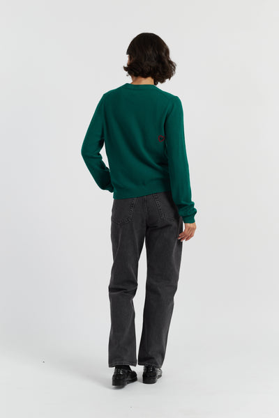 Person wearing a green sweater and gray pants on a white background