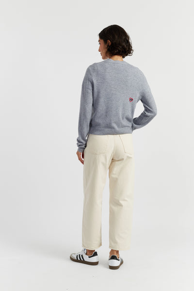 Person wearing a gray sweater and white pants on a white background