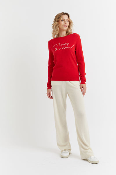 Woman wearing a red 'Merry Christmas' sweater on a white background