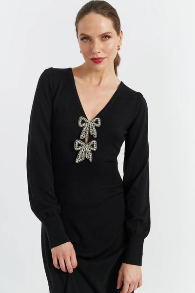 Black dress with bow embellishments worn by a model on a white background