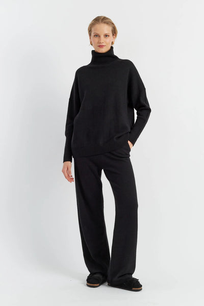 Person wearing a black turtleneck and pants on a white background