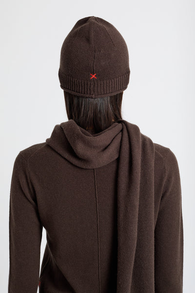 Person wearing a brown beanie and coat with a red logo on a white background