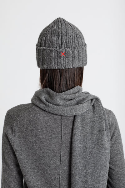 Person wearing a gray knit beanie and coat on a white background