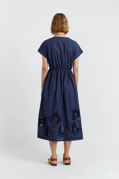 Woman wearing a navy dress with floral embroidery on a white background
