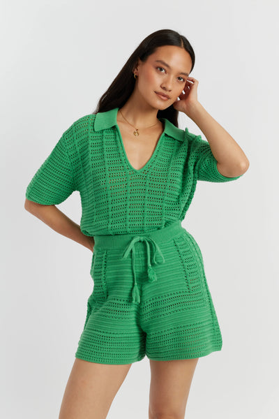 Woman wearing a green crochet romper against a white background