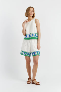 Woman wearing a white dress with green and blue floral patterns on a white background
