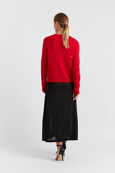 Woman wearing a red sweater and black skirt on a white background