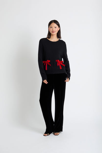 Woman wearing a black outfit with red bows on a white background