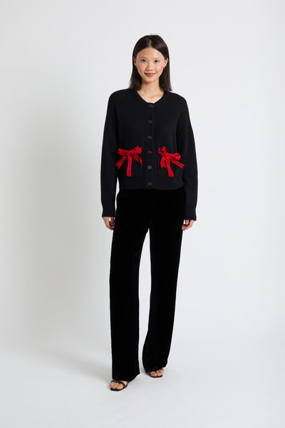 Woman wearing a black outfit with red bows on a white background