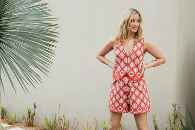 Woman wearing a red floral dress standing outdoors with plants in the background