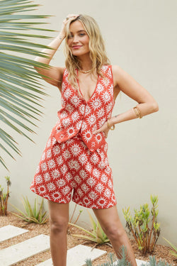 Woman wearing a red floral dress standing in a garden setting