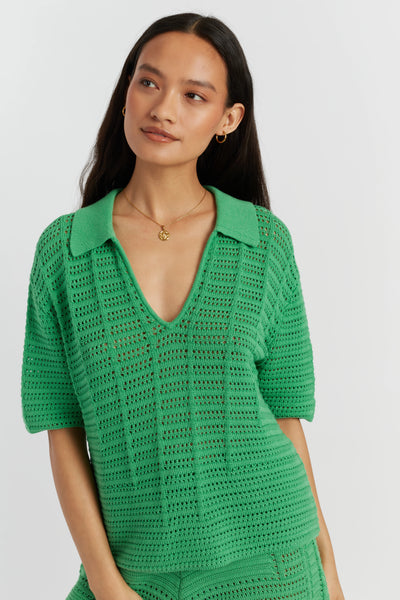 Woman wearing a green crochet top on a light gray background