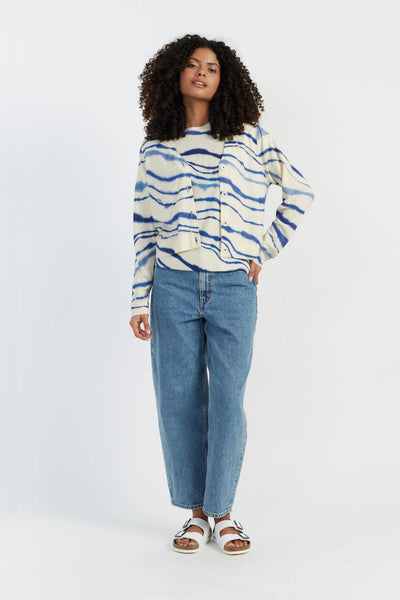 Woman wearing a blue and white striped sweater and jeans on a white background