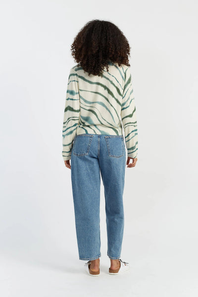 Person wearing a zebra-striped sweater and blue jeans on a white background