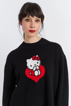 Person wearing a black sweater with a Hello Kitty design on a white background