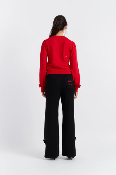 Person wearing a red sweater and black pants on a white background