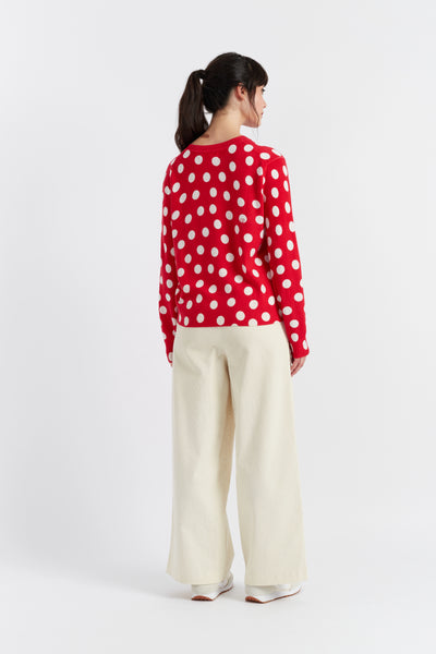 Person wearing a red polka dot shirt and white pants on a white background