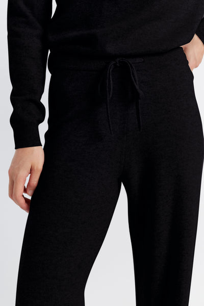 Person wearing a black outfit with a tie-waist design on a white background