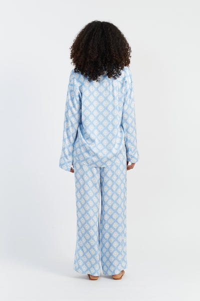 Person wearing a light blue patterned pajama set on a white background