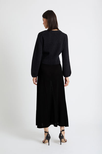 Woman wearing a black outfit with a long skirt on a white background