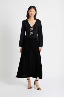 Woman wearing a black outfit with a deep neckline and decorative elements on a white background