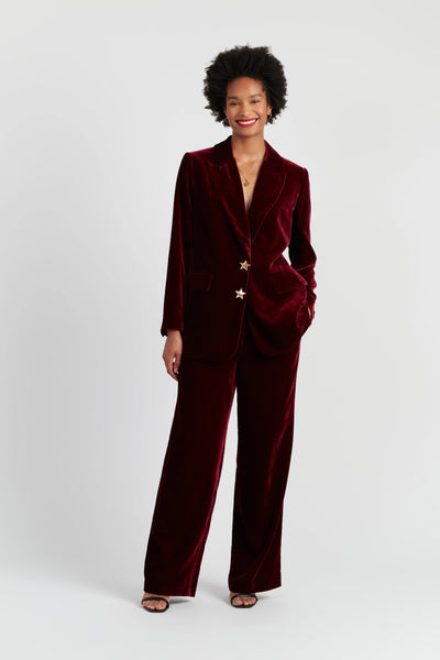 Woman wearing a burgundy velvet suit on a white background