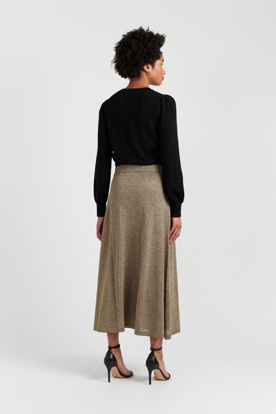 Woman wearing a black top and beige skirt on a white background