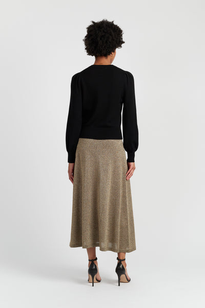 Person wearing a black top and beige skirt on a white background