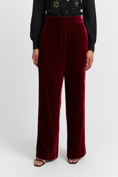 Maroon velvet pants worn by a person on a white background