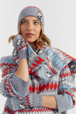 Person wearing a patterned sweater, scarf, and beanie with cartoon characters on a white background