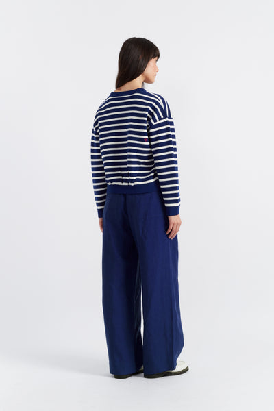 Person wearing a striped sweater and blue pants on a white background