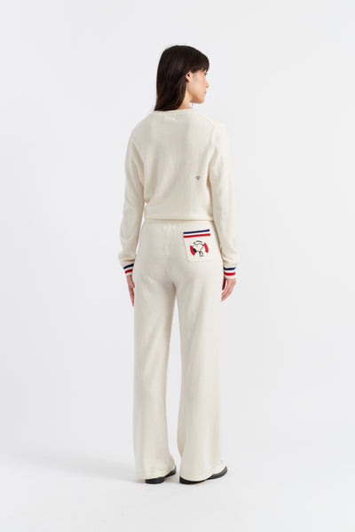 Woman wearing a cream-colored cardigan and pants with a small logo on a white background