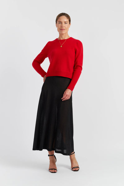 Woman wearing a red sweater and black skirt on a white background