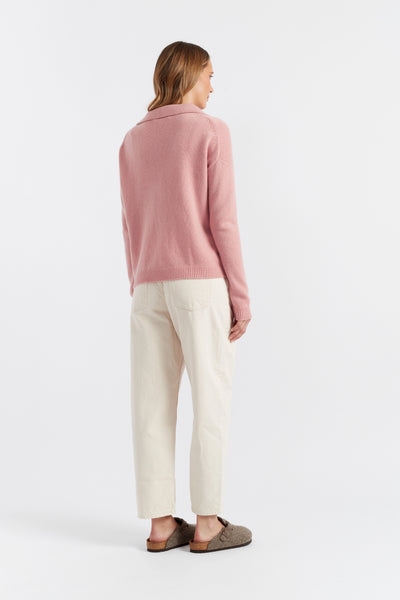 Woman wearing a pink sweater and pants against a plain background