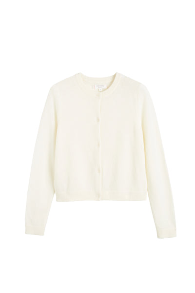 Woman wearing a beige sweater and pants against a white background