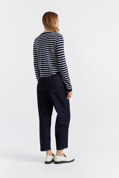 Person wearing a striped shirt and dark pants on a white background