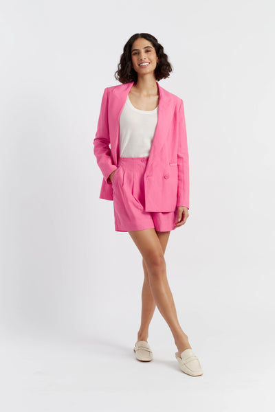 Woman wearing a pink suit with a white top on a white background