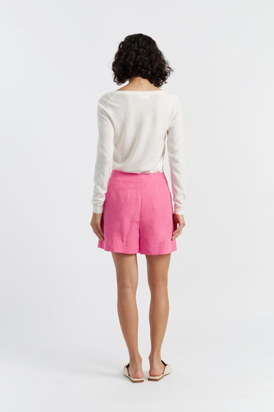 Person wearing a white long-sleeve shirt and pink shorts on a white background