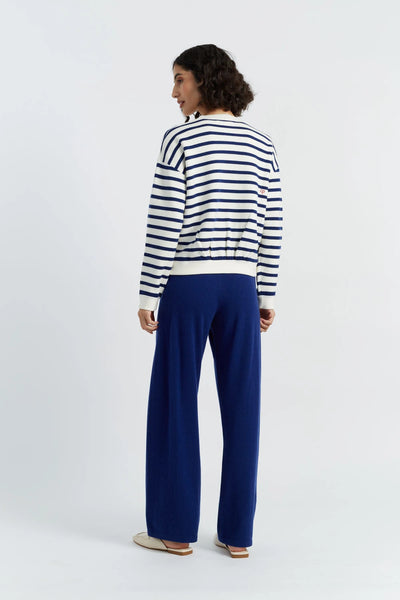 Woman wearing a striped sweater and blue pants on a white background