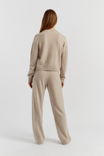 Person wearing a beige sweater and pants set on a white background