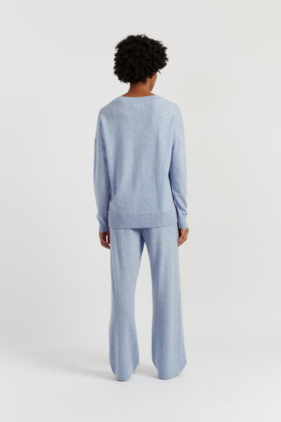 Person wearing a light blue sweater and pants set on a white background