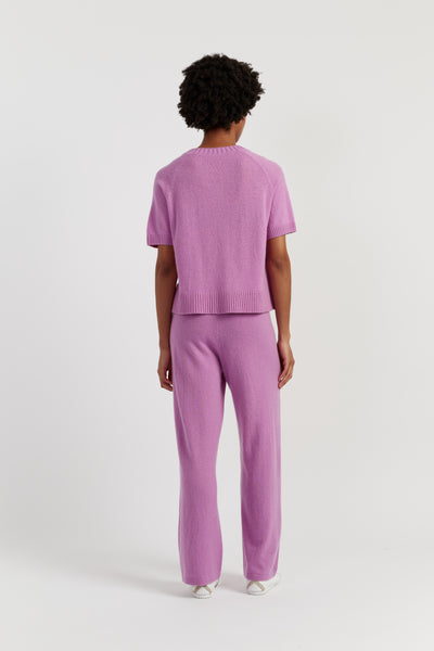 Person wearing a matching pink sweater and pants set on a white background