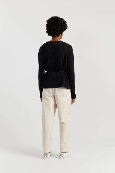 Person wearing a black top and white pants on a white background