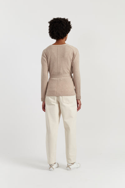Person wearing a beige sweater and white pants on a white background